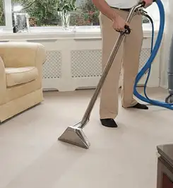 Professional carpet cleaner using a hot-water extraction wand and hose machine in a living room in Little Rock, AR.