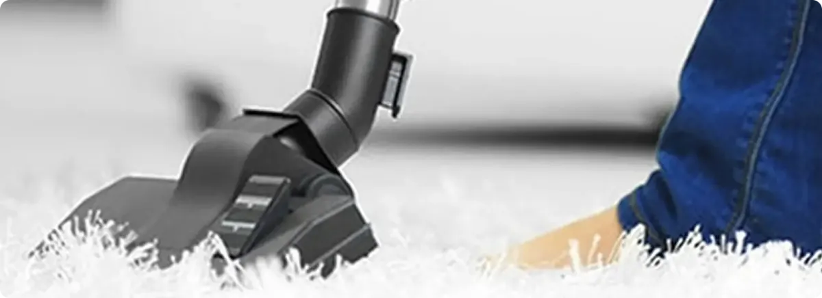 Close-up of a professional vacuuming a white carpet in Alexander.
