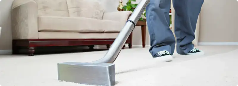 Carpet cleaning technician using a hot-water extraction wand on a light-colored carpet in a living room, Little Rock, AR.