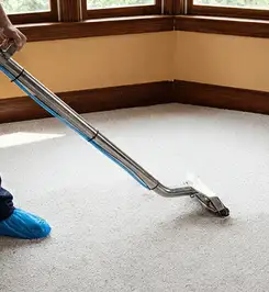 Steam carpet cleaning technician using a hot-water extraction wand on a residential carpet, wearing blue protective shoe covers Little Rock, AR.