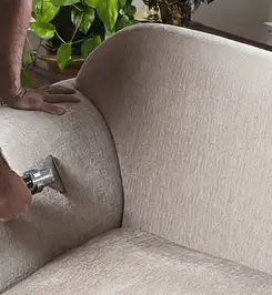 Professional upholstery cleaner deep-cleaning a fabric sofa with a handheld extraction tool and hose Little Rock, AR.
